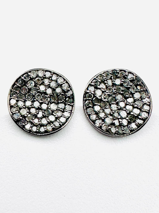 The JMNYC Designs Pave Diamond Wavy Disk Earrings feature round sterling silver studs adorned with pave-set white and dark stones in a swirling, wavy disk pattern, showcased against a plain white background.
