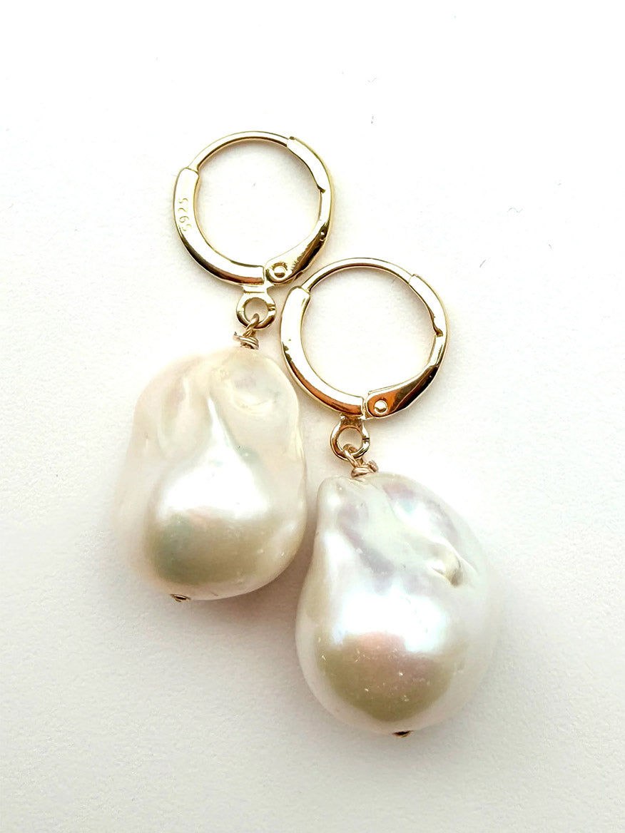 JMNYC Designs White Freshwater Baroque Pearl Earrings each showcase a large, irregularly shaped baroque pearl drop on a vermeil simple huggie leverback, measuring 1.5 inches and displayed against a white background.