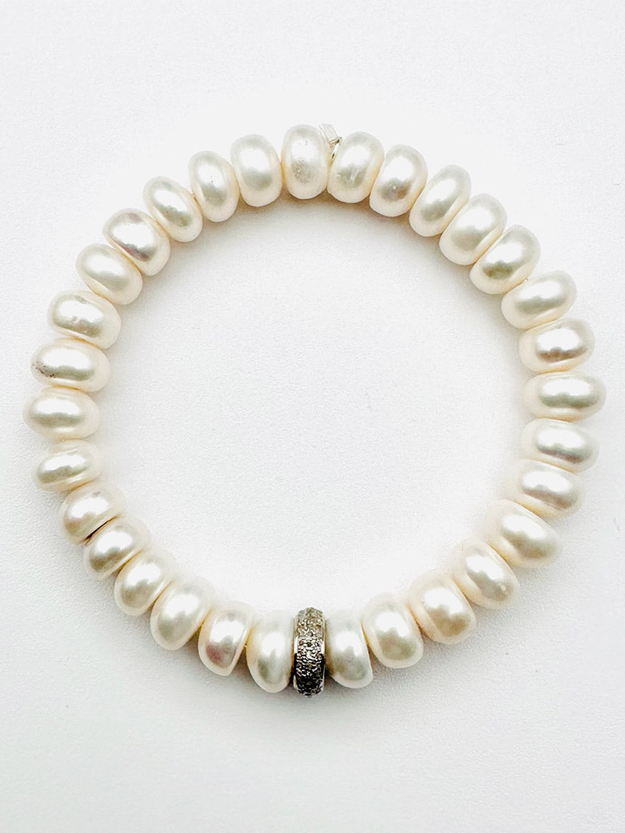 A JMNYC Designs White Freshwater Button Pearl Bracelet featuring lustrous white pearls and a three-row diamond rondelle accent, displayed on a white background.