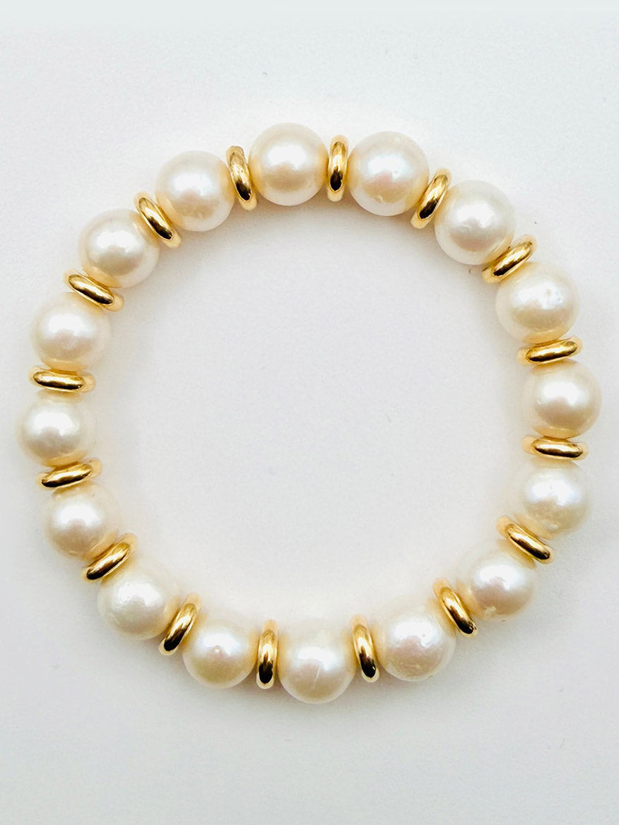 The JMNYC Designs White Freshwater Pearl and Gold Filled Rondelle Bracelet, 7.25", featuring white pearls separated by gold-filled spacers, is displayed on a plain white background.