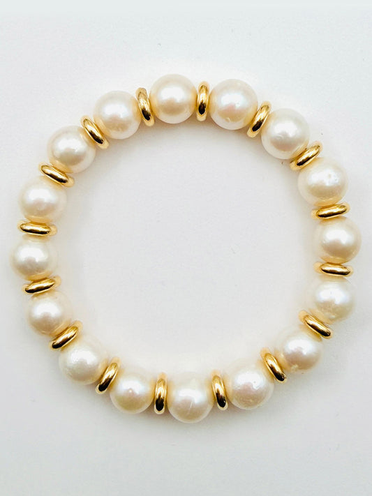 The JMNYC Designs White Freshwater Pearl and Gold Filled Rondelle Bracelet, 7.25", featuring white pearls separated by gold-filled spacers, is displayed on a plain white background.