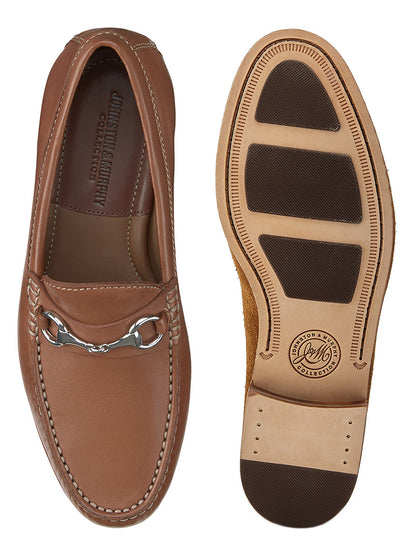 Top and sole view of the J & M Collection Baldwin Bit in Cognac Sheepskin, featuring a brown leather loafer with a metal bit design, sheepskin leather cushioned footbed displaying the "Johnston & Murphy" brand label, and rubber-treaded outsole.