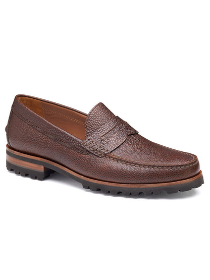 The J & M Collection Baldwin Lug Penny in Mahogany Scotch Grain loafer features a textured brown leather surface, penny slot detail, rubber sole, and a cushioned footbed for ultimate comfort.