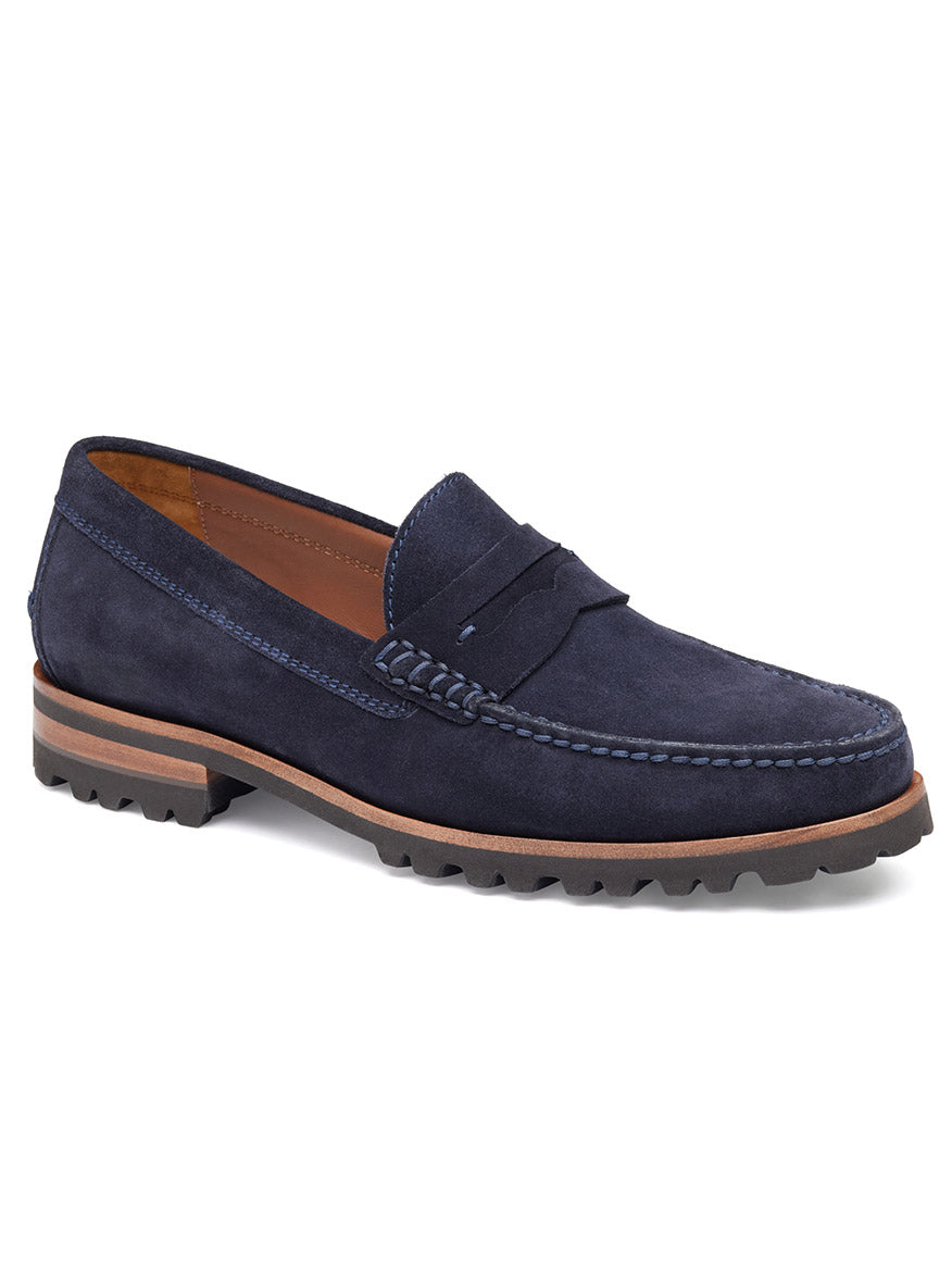 The J & M Collection Baldwin Lug Penny in Navy English Suede showcases decorative stitching, a brown midsole, and a textured black rubber sole. It boasts quality leather lining and traditional moccasin craftsmanship for superior comfort.