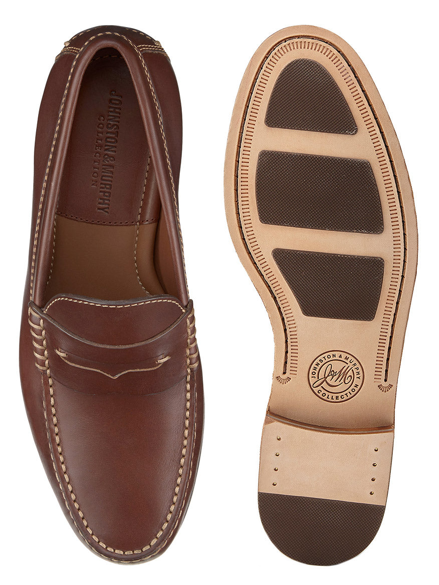 The J & M Collection Baldwin Penny in Brandy American Full Grain features brown leather loafers with stitched detailing and a rubber-soled heel. Showcasing handsewn moccasin craftsmanship, the left shoe is displayed from the top view, while the right shoe shows the sole.