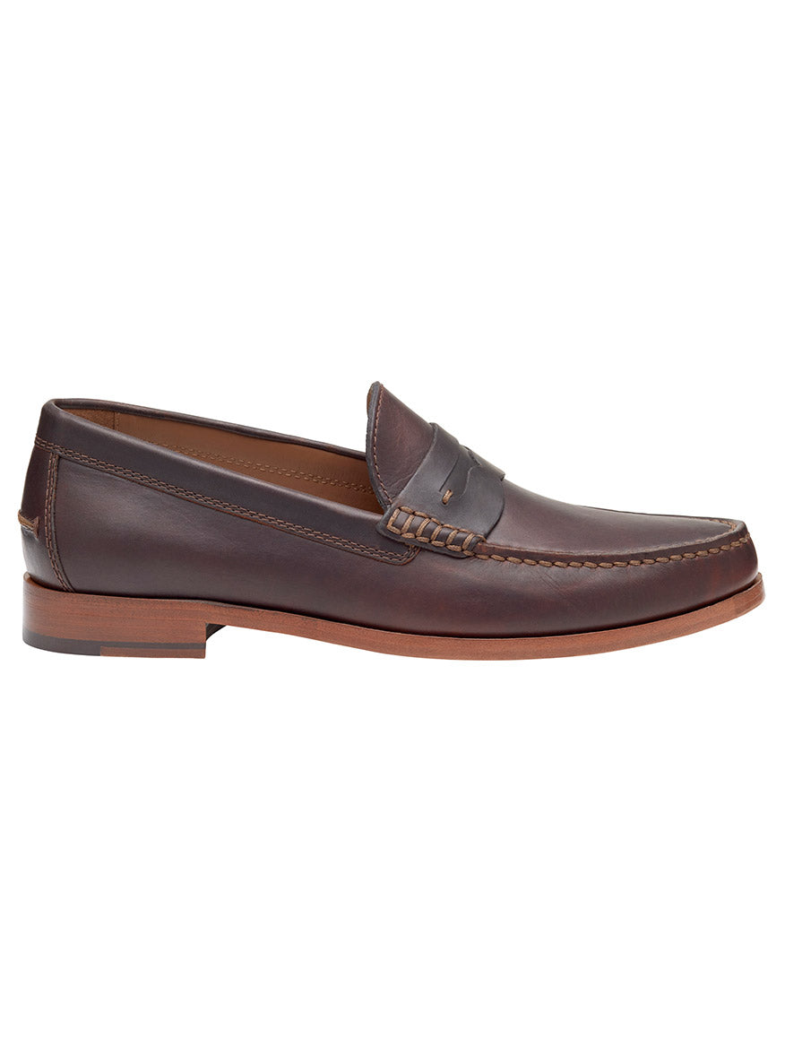 The J & M Collection Baldwin Penny in Dark Brown English Full Grain is a full-grain leather loafer featuring a handsewn moccasin-style toe, detailed stitching along the upper edge and sides, a low wooden heel, and a cushioned footbed for enhanced comfort.