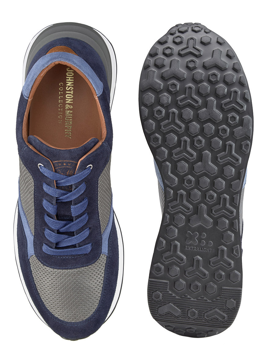 The J & M Collection Briggs Perfed Lace-Up in Navy/Grey/Blue Italian Suede/Calf shows one shoe from a top view and the other displaying the sole. Crafted from premium Italian suede and calf leather, these sneakers feature blue, gray, and brown tones. They boast a textured hexagonal pattern on the sole and ensure comfort with their advanced EVA outsole.