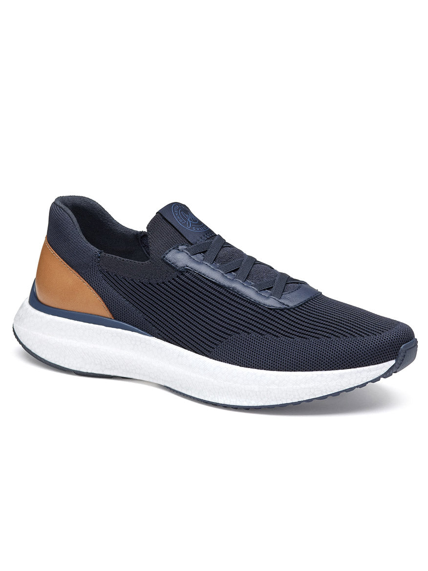 The J & M Collection Briley Knit Jogger in Navy Knit is an athletic sneaker featuring a navy blue body, a white sole, a brown leather accent on the heel, black laces, and a POWERFOAM midsole for exceptional cushioning.