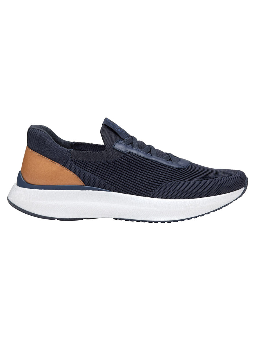 A side view of the J & M Collection Briley Knit Jogger in Navy Knit, featuring a white sole, tan accent on the heel, and breathable knit uppers for added comfort.