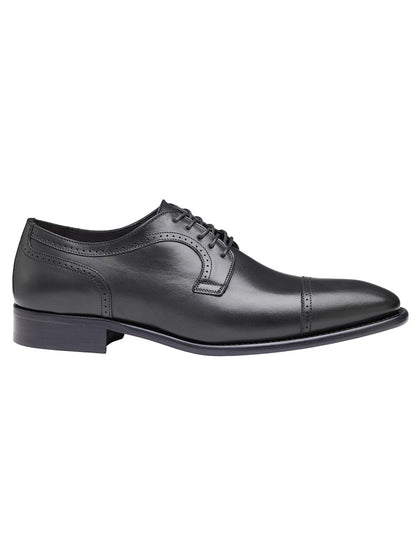 The J & M Collection Cormac Cap Toe in Black Italian Calfskin by Johnston & Murphy features black leather, a closed lacing system, a slight heel, a plain toe cap, and a comfortable leather footbed.