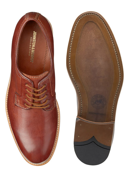 A pair of brown, tanned leather dress shoes displayed with one shoe flipped to reveal the sole featuring Goodyear welt construction - J & M Collection Dudley Plain Toe in Tan Dip-Dyed Calfskin.