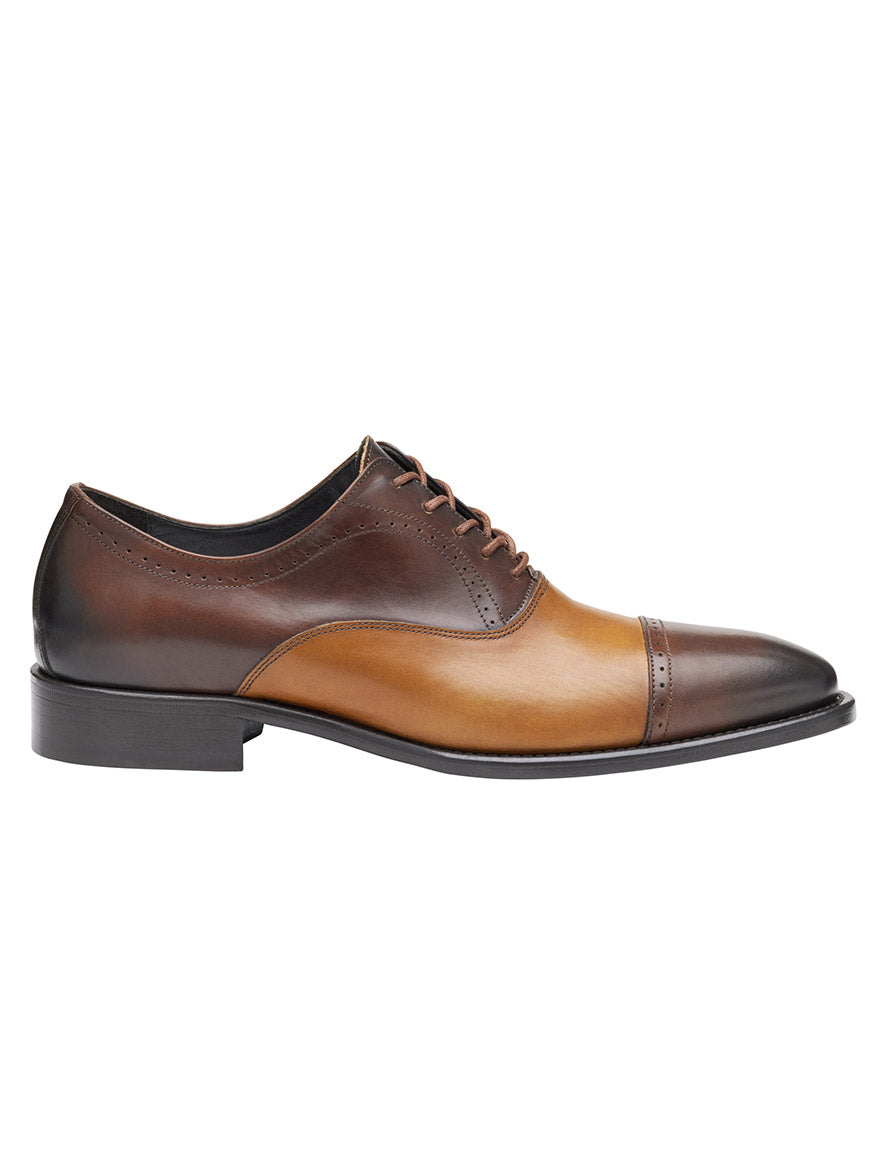 The J & M Collection Ellsworth Cap Toe Balmoral is a brown and tan leather oxford shoe made from Italian calfskin, featuring a cap toe design, black sole, and luxurious leather lining.