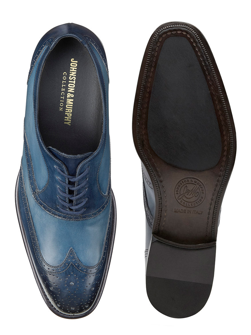 A pair of J & M Collection Ellsworth Wingtip in Navy Italian Calfskin dress shoes with decorative perforations and embossed branding on the insole, viewed from above.