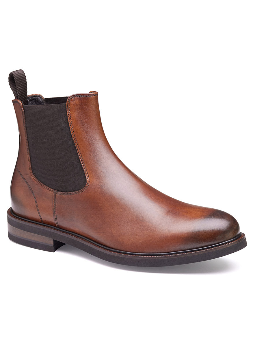 The J & M Collection Hartley Chelsea Boot in Brown Italian Calfskin is a brown leather Chelsea boot crafted from Italian calfskin. It features an elastic side panel, a pull tab at the back, a leather lining, and a dark brown sole with a Vibram® EVA outsole. The boot also boasts a slightly rounded toe.