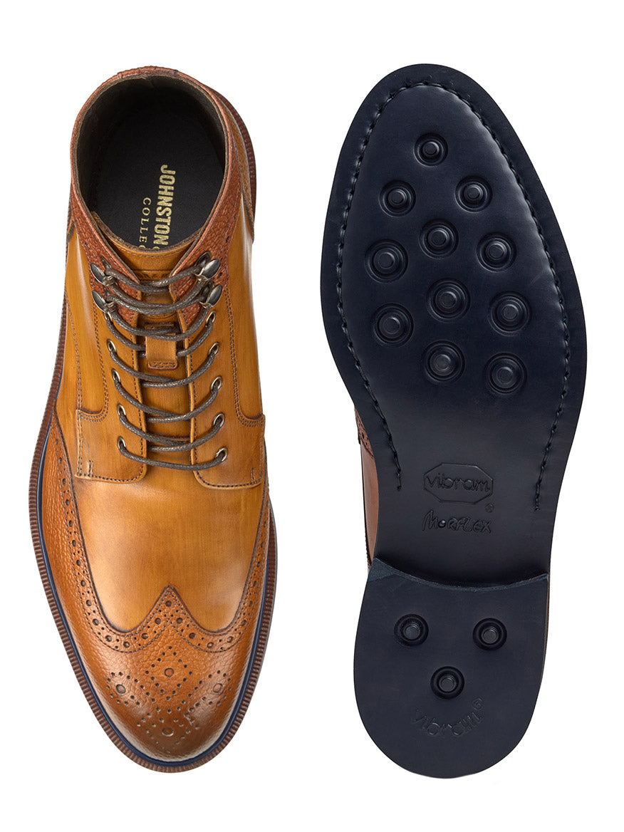 A tan Hartley Wingtip Boot in hand-stained calfskin from the J & M Collection is shown from the top and bottom. The top view highlights the laces and perforated design, while the bottom view reveals a black Vibram EVA outsole with circular tread patterns.