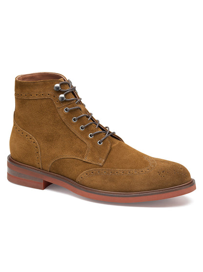 The J & M Collection Hartley Wingtip Boot in Snuff Italian Suede is a brown, Italian suede lace-up boot with decorative perforations on the toe and sides, featuring a red-brown sole, leather lining, and a slightly raised heel.