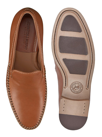 The J & M Collection Baldwin Venetian in Cognac Sheepskin presents brown loafers with top and sole views displayed. They exhibit a moccasin construction, offer cushioned footbeds for superior comfort, and the soles include two textured dark gray grip panels.