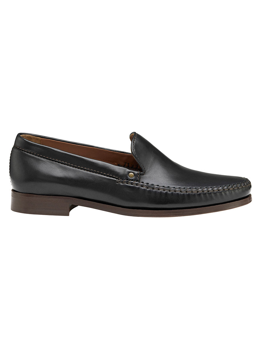 The J & M Collection Baldwin Venetian in Black Sheepskin is a loafer with a brown sole and side stitching, featuring a cushioned footbed for enhanced comfort.