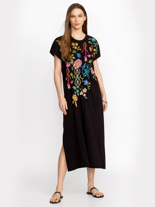 Woman wearing a Johnny Was Sheri Relaxed Knit Dress in Black with colorful placement embroidery standing against a light gray background.
