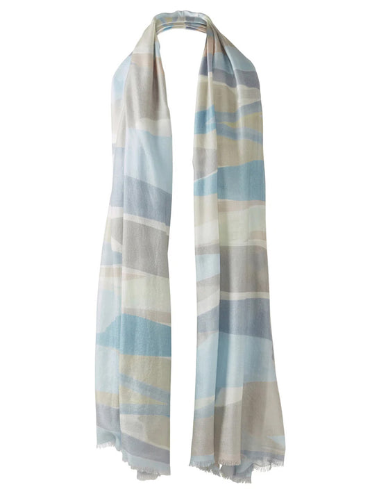 The Kinross Abstract Landscape Print Scarf in Skyway Multi is a long, lightweight scarf with a blue, beige, white, and gray abstract landscape pattern and fringed edges.