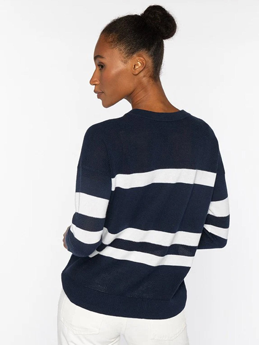 A woman with her hair in a bun wears the Kinross Mesh Stripe Crew in Denim/Greystone and white pants, standing against a plain light background.