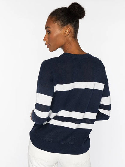 A woman with her hair in a bun wears the Kinross Mesh Stripe Crew in Denim/Greystone and white pants, standing against a plain light background.