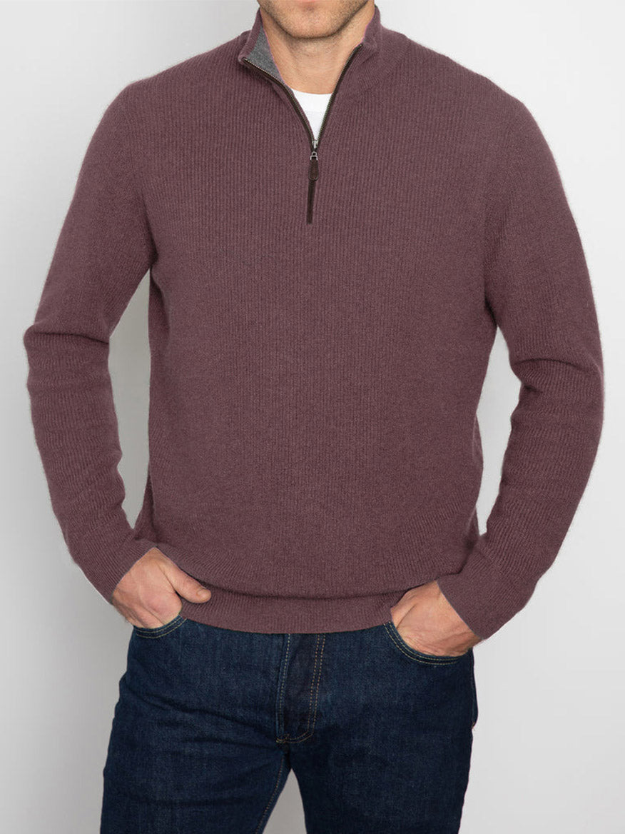 A person wearing the Kinross Suede Trim Rib Quarter Zip Mock Sweater in Seal/Flannel, paired with dark jeans, stands against a light gray background.