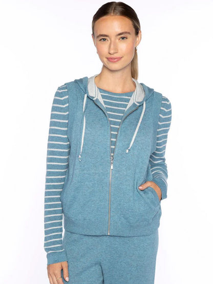 A woman wears the Kinross Sleeveless Zip Hoodie in Denim, standing against a plain white background.
