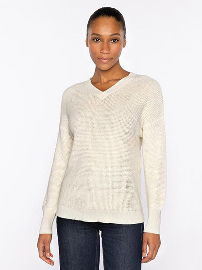 A woman faces forward wearing the Kinross Thermal Sequin Vee in Cream, a premium cotton knit sweater with long sleeves, paired with dark jeans, set against a plain white background.