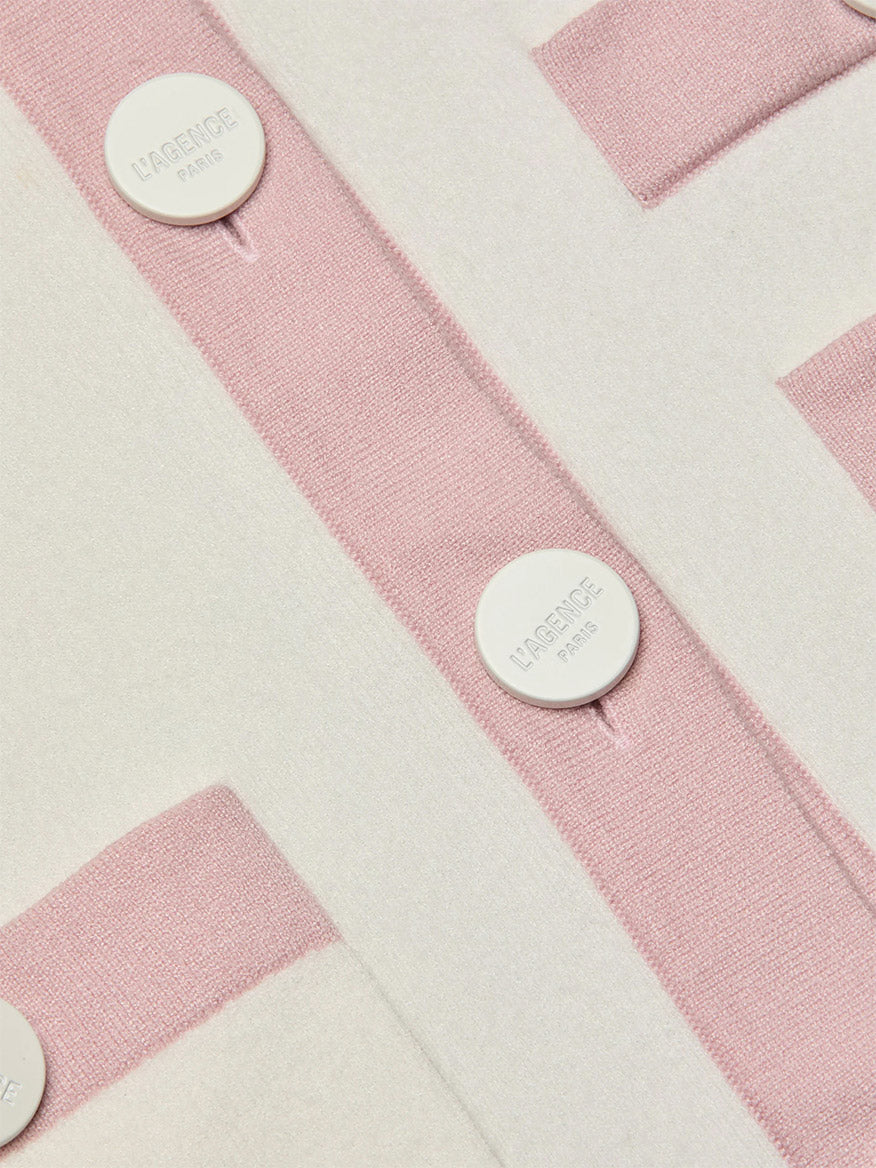 Close-up of the L'Agence Nomi Satin Back Cardigan in Ivory/Pink/Multi Butterfly Jungle, featuring cream and pink contrast trim and white "L’AGENCE PARIS" statement buttons sewn along the pink stripes.