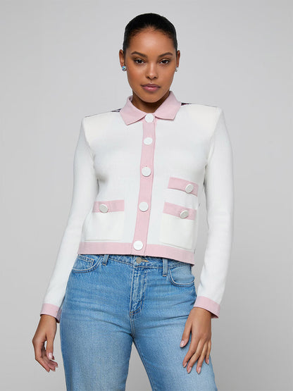 Woman wearing the L'Agence Nomi Satin Back Cardigan in Ivory/Pink/Multi Butterfly Jungle with contrast trim and statement buttons, paired with blue jeans, stands against a light gray background.