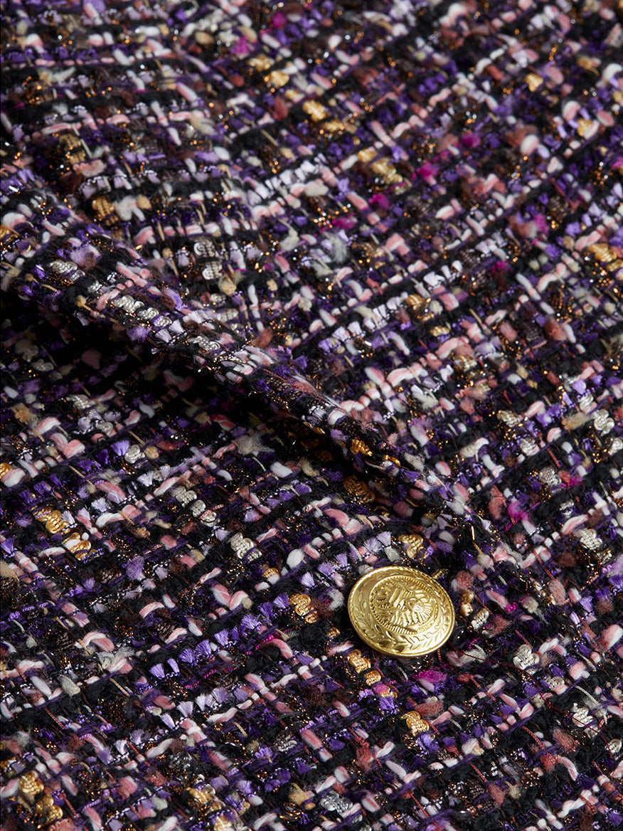 A close-up of the L'Agence Chamberlain Tweed Blazer in Purple Multi displays a textured stretch knit fabric featuring a plaid pattern in shades of purple, pink, and gold, accented with an embossed dome button.