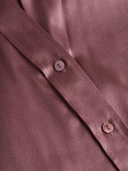 Close-up of a buttoned section of the L'Agence Dani Blouse in Mauve Rose, featuring embossed dome buttons on a silky fabric.