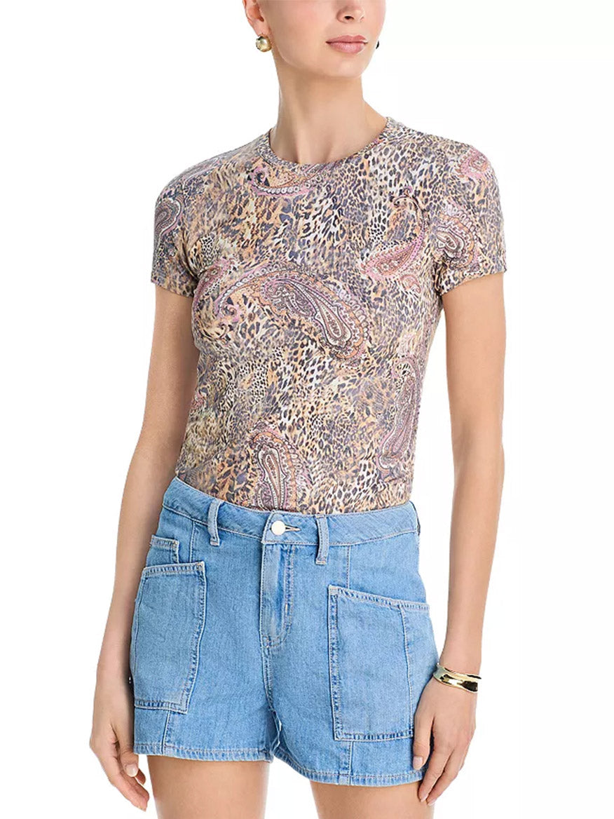 A woman wears the L'Agence Ressi Fitted Tee in Valencia Leopard with high-waisted, light blue denim shorts featuring large front pockets.