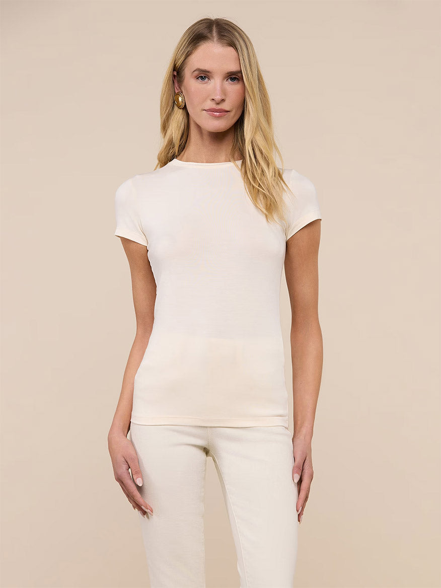 Woman wearing the L'Agence Ressi Fitted Tee in Vintage White, styled with matching pants, standing against a plain beige background.