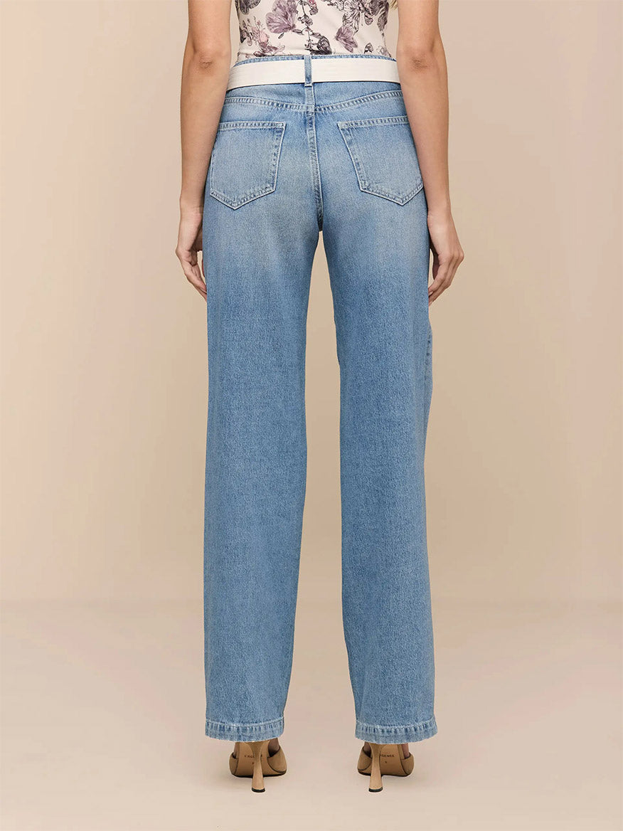 Model shown from the back in L'Agence Scottie Wide-Leg Jean in Grant, a light indigo wash high-rise denim, paired with beige heeled shoes against a neutral background.