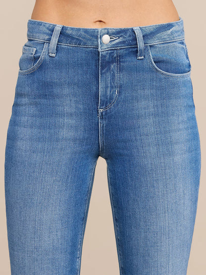 Close-up of a person wearing the L'Agence Selma Bootcut Jean in Sullivan—high-waisted, light blue stretch denim jeans with a button and zipper closure, front pockets, and belt loops. Only the waist and upper legs are visible.