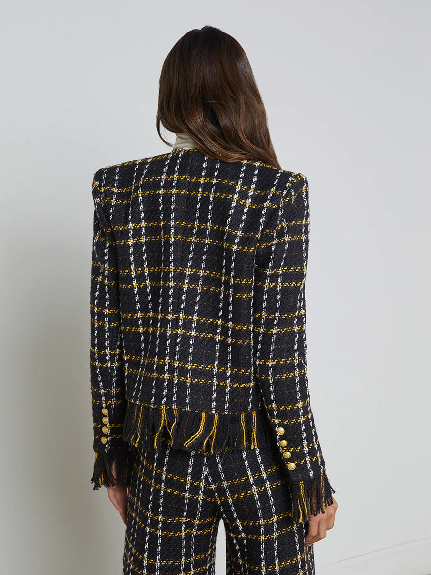 A person with long hair is wearing the L'Agence Belmont Fringe Jacket in Black Yellow Multi Plaid and matching pants, viewed from the back.