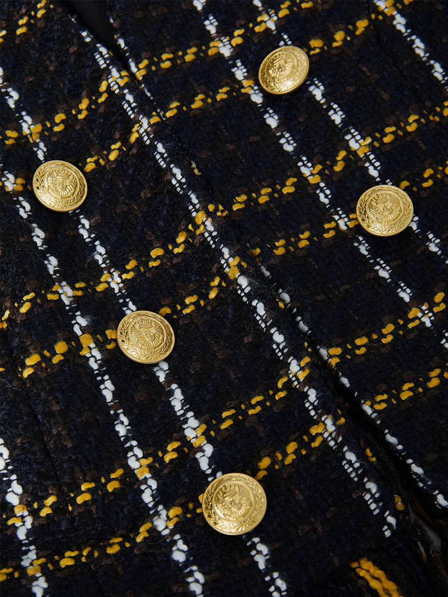 Close-up of the L'Agence Belmont Fringe Jacket in Black Yellow Multi Plaid, featuring gold buttons with an embossed design and subtle fringe trim.