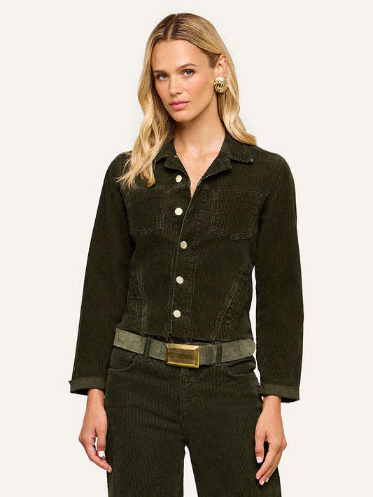 Wearing the L’Agence Janelle Corduroy Jacket in Army, paired with matching slim fit pants, a wide belt, and gold earrings, the woman stands against a plain light background.