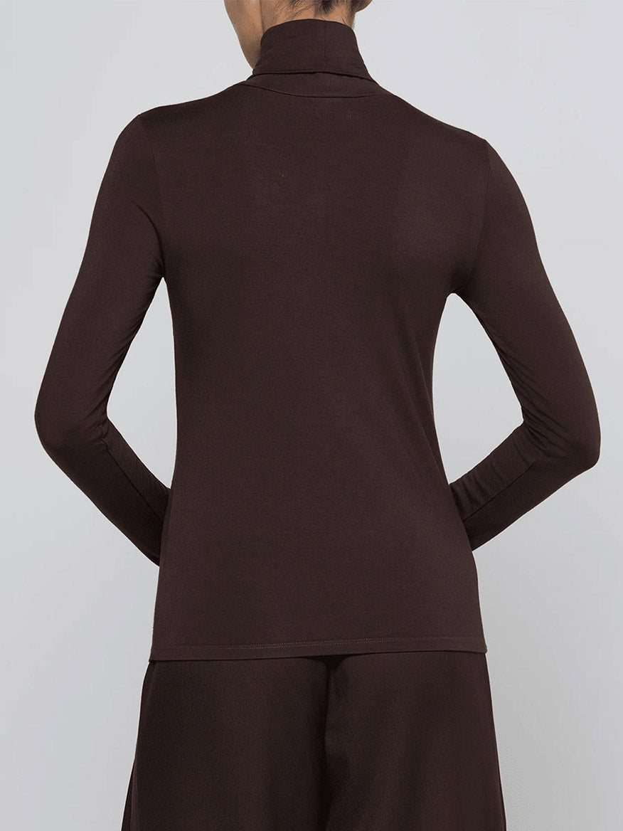 Person seen from the back wearing the L’Agence Lani Turtleneck in Dark Java, a slim fit, long-sleeve top, paired with matching dark brown pants.
