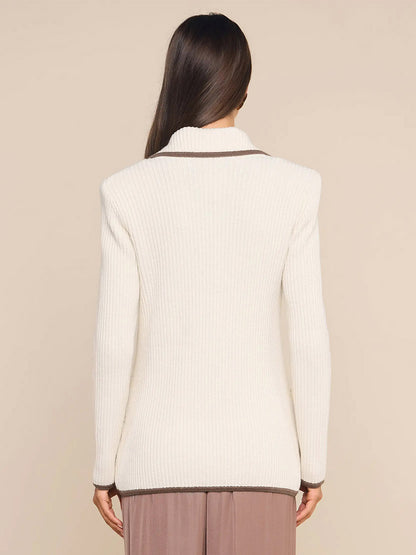 A woman with long brown hair, shown from the back against a neutral background, is wearing the L’Agence Ranch Knit Blazer in Ivory/Dark Cappuccino, featuring a cream-colored ribbed knit design with contrasting brown trim.