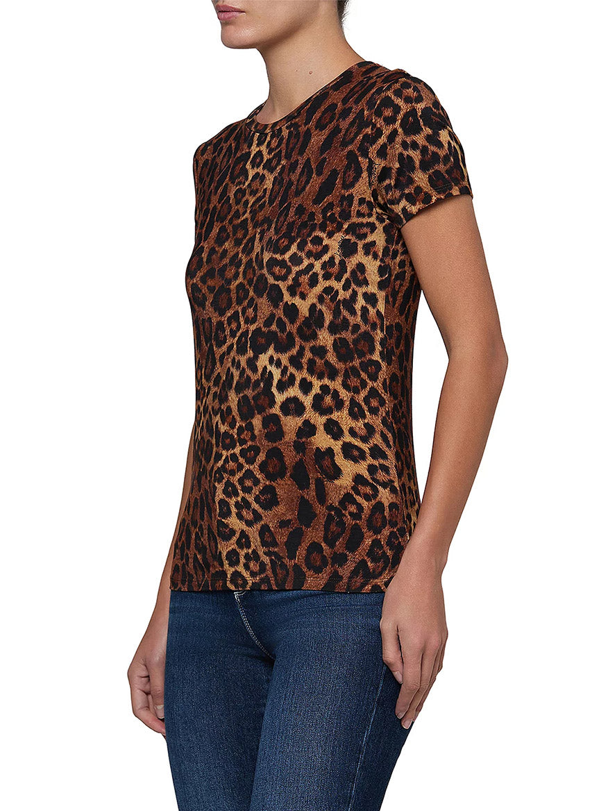 A person wearing the L’Agence Ressi Short Sleeve Crew in Tan Multi Javan Leopard and blue jeans, standing against a white background.