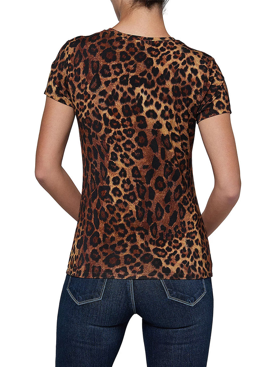 A person is shown from behind against a white background, wearing dark blue jeans and the L’Agence Ressi Short Sleeve Crew in Tan Multi Javan Leopard—a women’s lightweight leopard print tee.