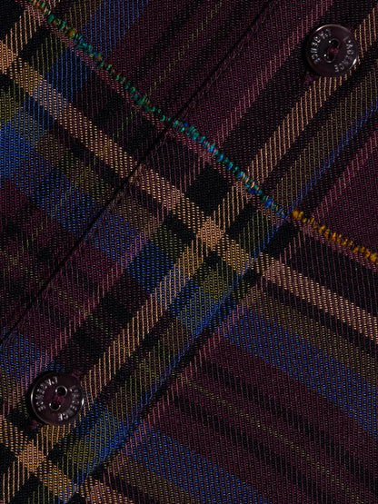 Close-up of the L’Agence Suzette Shirt in Dark Plum Multi Plaid, featuring diagonal multicolored plaid with visible blue and yellow lines, two black buttons, and contrasting stitching along the seam.