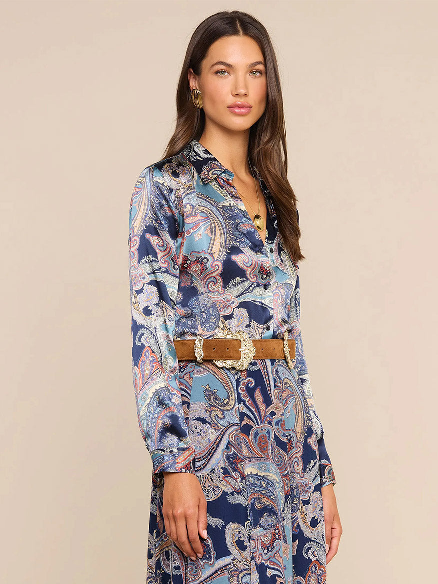 Woman wearing the L’Agence Tyler Blouse in Midnight Multi Besarabian Paisley, styled with a tan belt and standing against a plain background while looking toward the camera—an effortlessly chic look evocative of L’AGENCE style.