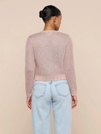 Woman stands with her back to the camera in the L'Agence Blanca Sequin Cardigan in Adobe Rose and light blue high-waisted jeans, set against a plain beige background.