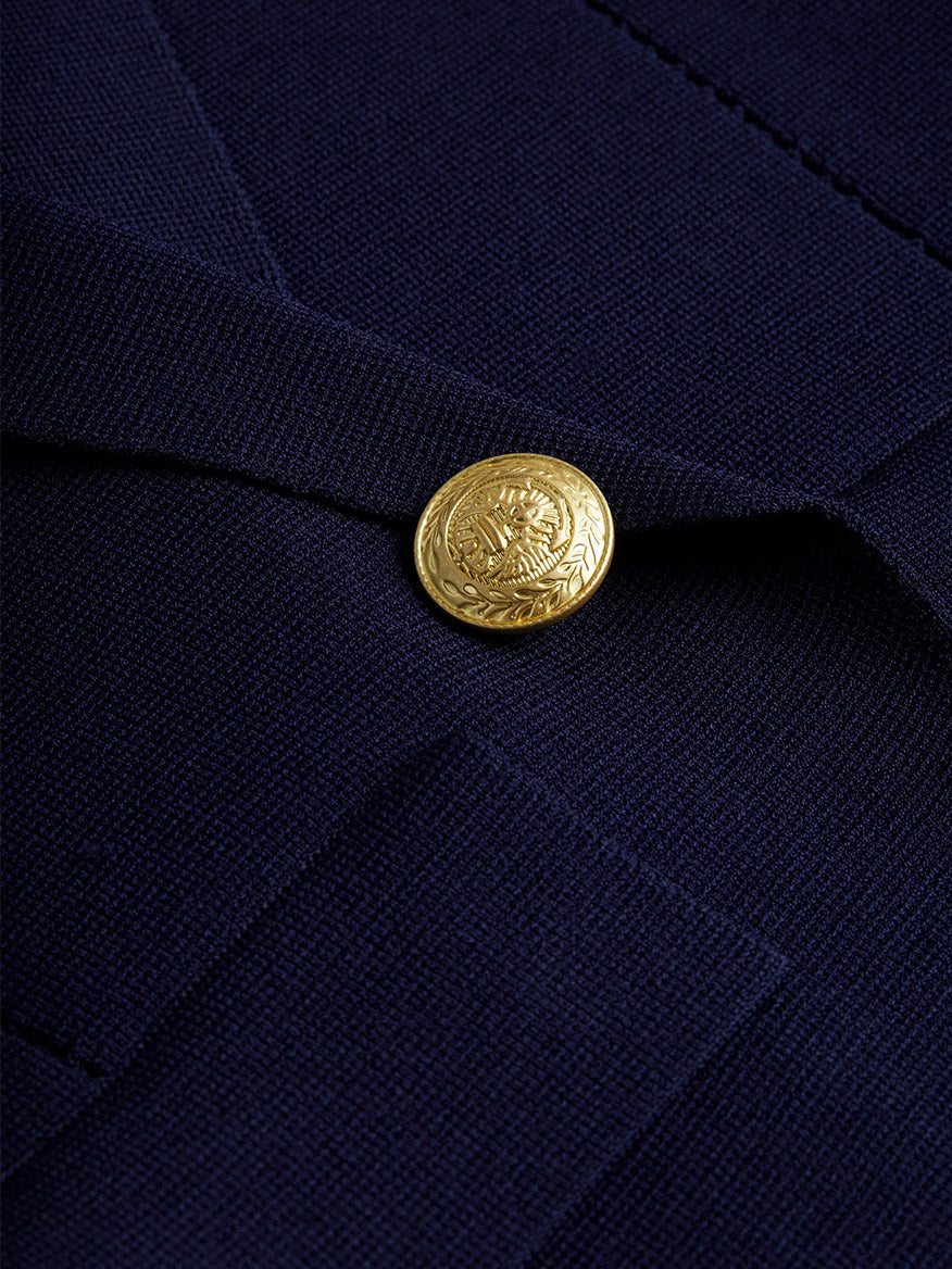 Close-up of the L'Agence Chamberlain Knit Blazer in Midnight/Gold, showcasing the navy blue fabric adorned with a single embossed dome button featuring an intricate, circular design.