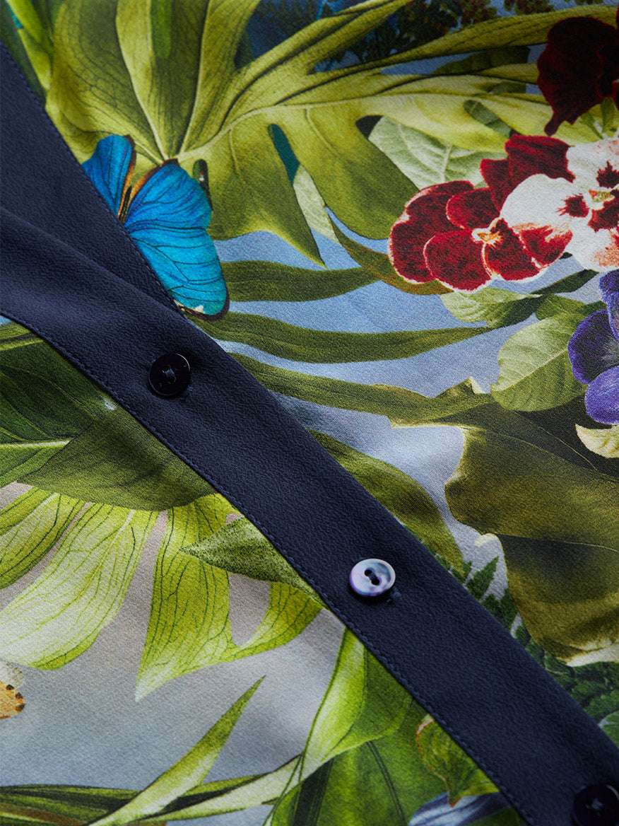 Close-up of the L'Agence Charlize Tie-Front Silk Blouse in Multi Lush Jungle, featuring a 100% silk fabric with a floral and butterfly print, buttons running down the center, and dramatic bell sleeves.