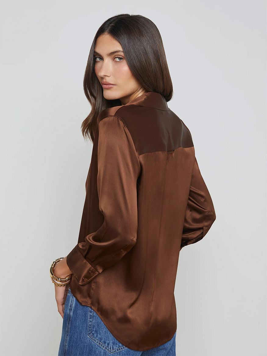 Woman in the L'Agence Dani Blouse in Hot Fudge and jeans, standing sideways.